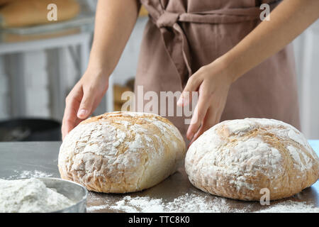 Baker, die Überprüfung von frisch gebackenen Brotes in der Bäckerei Küche Stockfoto