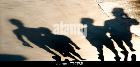 Verschwommene Schatten Silhouetten von jungen Menschen zu Fuß auf Sommer Sonnenuntergang promenade Stockfoto