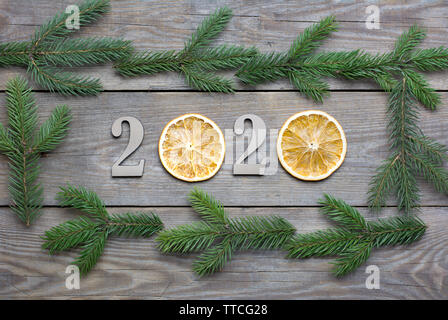 2020 Neue Jahr rustikalen Hintergrund mit Orangenscheiben und Tannenbaum Äste auf Holzplatten Stockfoto