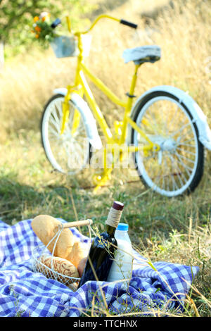 Alte gelbe Fahrrad und Picknick Snack auf karierten Decke auf Gras im Park Stockfoto