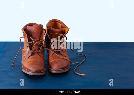 Alte Rot schmutzig hohe Schuhe auf blauem Hintergrund. Alte Schule vintage getragen Stiefel mit Lederbändern. Stockfoto