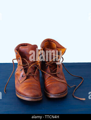 Alte Rot schmutzig hohe Schuhe auf blauem Hintergrund. Alte Schule vintage getragen Stiefel mit Lederbändern. Stockfoto