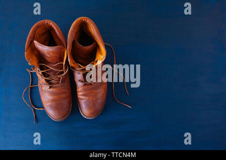 Alte Rot schmutzig hohe Schuhe auf blauem Hintergrund. Alte Schule vintage getragen Stiefel mit Lederbändern. Stockfoto