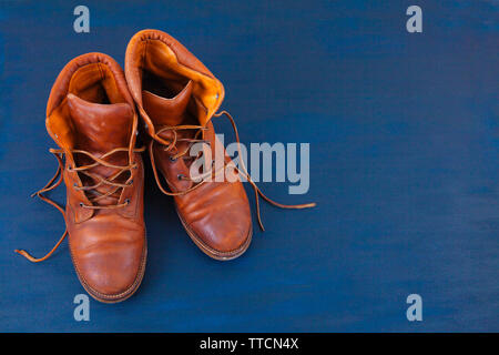 Alte Rot schmutzig hohe Schuhe auf blauem Hintergrund. Alte Schule vintage getragen Stiefel mit Lederbändern. Stockfoto