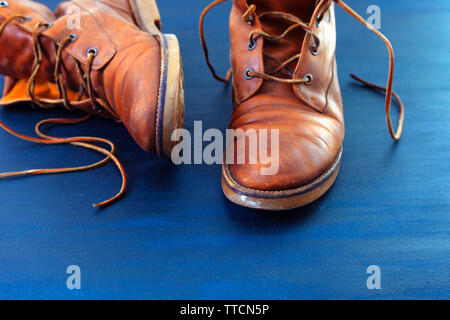 Alte Rot schmutzig hohe Schuhe auf blauem Hintergrund. Alte Schule vintage getragen Stiefel mit Lederbändern. Stockfoto