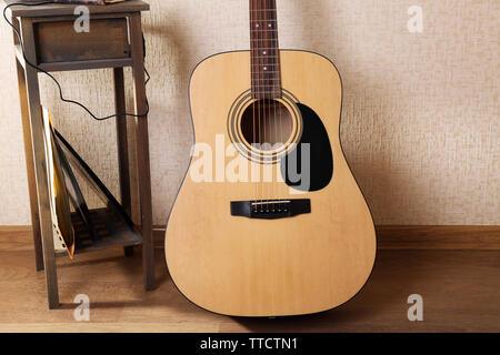 Akustik Gitarre stützte sich an der Wand mit Hocker und Kopfhörer im Zimmer, in der Nähe Stockfoto