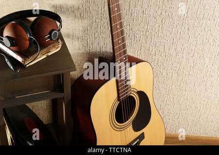 Akustik Gitarre stützte sich an der Wand mit Hocker und Kopfhörer im Zimmer, in der Nähe Stockfoto