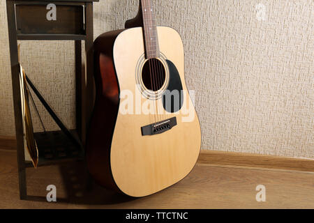 Akustik Gitarre stützte sich an der Wand mit Hocker und Kopfhörer im Zimmer, in der Nähe Stockfoto