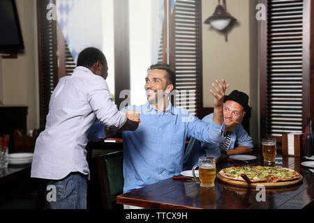 Junge Männer trinken Bier und Gespräch im Cafe Stockfoto