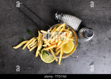 Pommes Frites mit Zitrone und Salz in Sieb auf Tisch Stockfoto