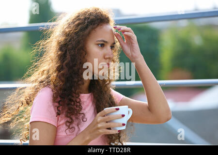 Hübsche, junge Frau im rosa Kleid trinken Kaffee im Sommer Terrasse Stockfoto