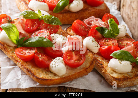 Leckere Ciabatta mit Mozzarella, Tomaten, Schinken und Basilikum close-up auf dem Tisch. Horizontale Stockfoto