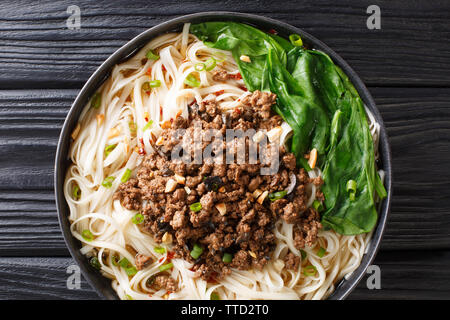 Traditionelle Chinesische Sichuan Dan Dan Nudeln mit Hackfleisch und Grüns in einen Teller auf dem Tisch. Horizontal oben Ansicht von oben Stockfoto