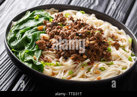 Traditionelle Chinesische Sichuan Dan Dan Nudeln mit Hackfleisch und Grüns in einen Teller auf dem Tisch. Horizontale Stockfoto