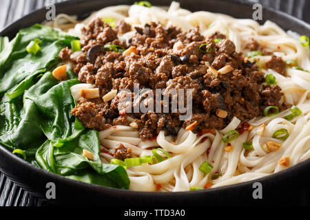Sichuan Dan Dan Nudeln mit Hackfleisch und Grünen closeup in einem Teller auf dem Tisch. Horizontale Stockfoto