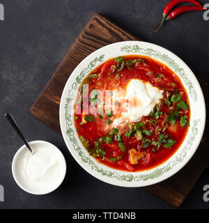 Traditionelle ukrainische russische traditionelle Rüben rote Suppe - borschtsch mit saurer Sahne auf schwarzem Stein. Ansicht von oben. Stockfoto