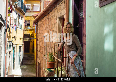 Junge Frau, die auf der Veranda im Innenhof der Altstadt, Porto, Portugal. Stockfoto