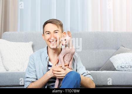 Jungen gutaussehenden Mann sitzend mit Katze auf dem Boden zu Hause Stockfoto