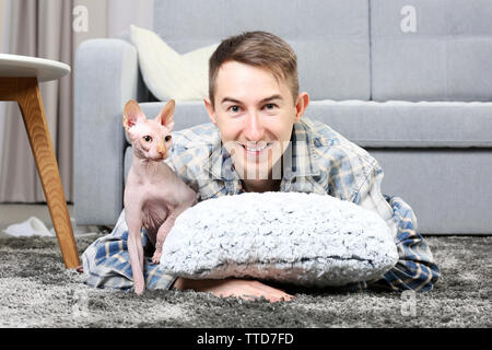 Jungen gutaussehenden Mann liegt mit Katze auf dem Boden zu Hause Stockfoto