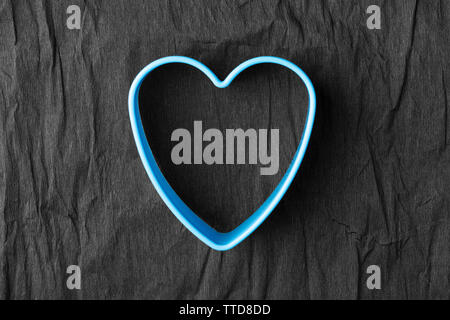 Blaues Herz Form auf Zerknitterten schwarzen Papier. Das Konzept der Valentinstag und unkonventionelle Paare Stockfoto