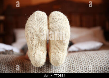 Die Beine der Frau in warme Socken auf dem Bett Stockfoto