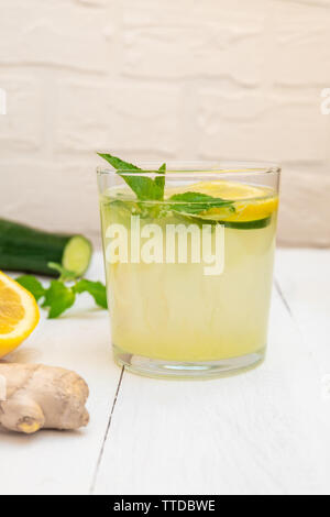 Glas von Sassy Wasser mit Zutaten (Zitrone, Ingwer, Minze, Gurke) auf die weiße Holztisch Stockfoto