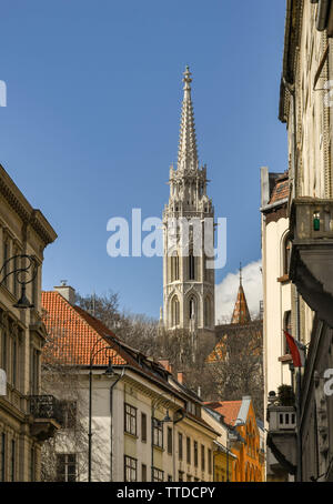 BUDAPEST, Ungarn - März 2018: Der Turm der Matthiaskirche in Budapest. Die Aussicht ist durch Gebäude in der Straße, die bis zur Kirche umrahmt. Stockfoto