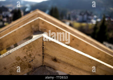 Close-up Detail der Dachrahmen aus grobem Holz Bauholz Balken auf dem Hintergrund von Misty Mountain Landschaft im ökologischen Bereich. Gebäude, Dach, constructi Stockfoto