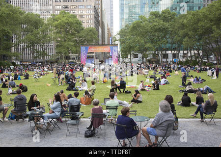 Touristen und New Yorker entspannen sich auf dem Gras im Bryant Park hinter der New York Public Library entlang der 42nd Street zwischen 5th und 6th Avenue in Th Stockfoto