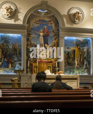 Die Leute, die auf der Suche nach innen und oben im Gebet an einer katholischen Kirche in Midtown Manhattan. Stockfoto