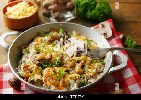 Gebratene Pilze, Huhn und Käse überbacken in Pan, auf hölzernen Hintergrund Stockfoto
