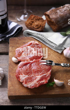 Marmorierte Rindfleisch Steak mit einer Flasche Wein und Gewürzen auf Holz- Hintergrund Stockfoto