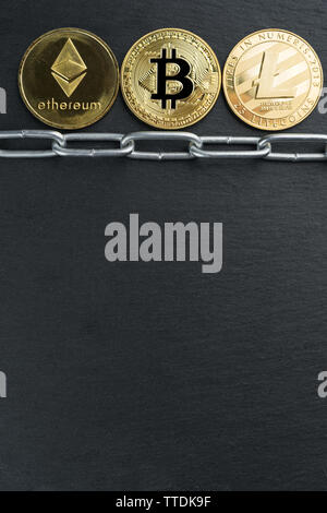 Physische Bitcoin, Litecoin und des Astraleums Gold Münzen auf einen schwarzen Stein Schiefer Platte mit Kette. Cryptocurrency blockchain abstraktes Konzept. Stockfoto