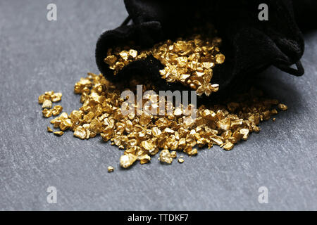 Eine Tasche mit verstreuten Gold Nugget Körner, auf Zement Hintergrund Stockfoto