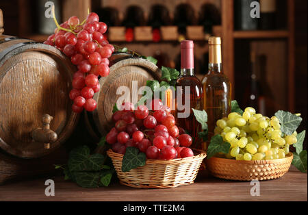 Trauben in Schüsseln und Faß auf hölzernen Tisch Stockfoto