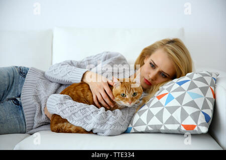 Junge Frau mit rote Katze auf Sofa Stockfoto