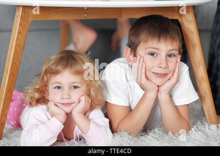 Süße kleine Kinder spielen unter dem Tisch Stockfoto