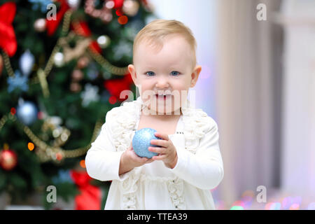 Lustige Baby Mädchen mit Geschenk Boxen in der Nähe von Weihnachten Baum auf hellen Hintergrund Stockfoto