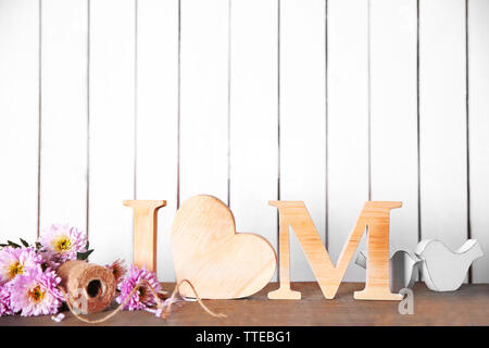 Holz- briefe mit Herzen und Blumen auf weiß Wand Hintergrund Stockfoto