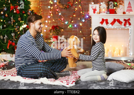 Der ältere Bruder und kleine Schwester einen Teddybären in Weihnachten Wohnzimmer Stockfoto