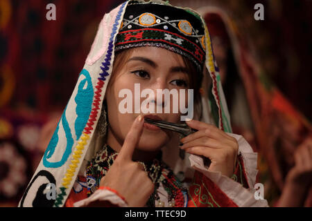 Junge usbekische Frau in traditionellen bestickten Kostümen im Surkhandarya-Stil, die Maultrommel spielt, die von den Turkvölkern in der Stadt Jarkurgan in Surkhandarya oder der Surxondaryo-Region in Usbekistan verwendet wird Stockfoto