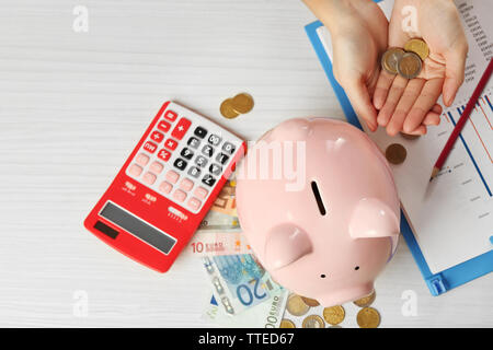 Woman's Hand, die Euro-Münzen auf den Tisch. Finanzielle Einsparungen Konzept Stockfoto