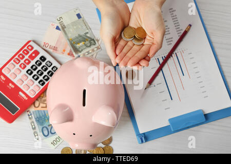 Woman's Hand, die Euro-Münzen auf den Tisch. Finanzielle Einsparungen Konzept Stockfoto