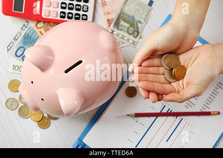 Woman's Hand, die Euro-Münzen auf den Tisch. Finanzielle Einsparungen Konzept Stockfoto