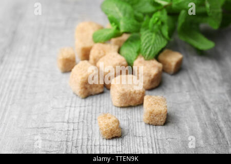 Stapel von Brown Sugar Cubes und Stevia auf grau Holz- Hintergrund Stockfoto