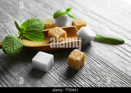 Stapel von Brown Sugar Cubes und Stevia auf grau Holz- Hintergrund Stockfoto