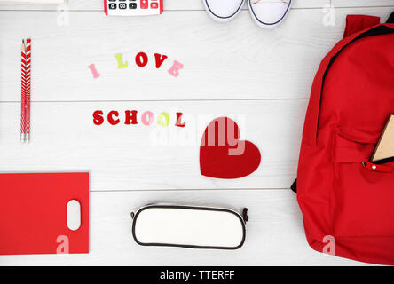 Schule mit Rucksack, Herz und Lieferungen auf hellen Hintergrund einstellen Stockfoto