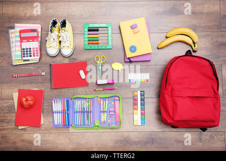 Schule mit Rucksack, Schuhe und Zubehör auf hölzernen Hintergrund Stockfoto