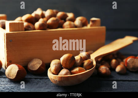 Haselnüsse in der Holzkiste und Löffel auf dem Tisch, Nahaufnahme Stockfoto