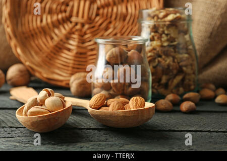 Mix der Schalenfrüchte in der Gläser und Löffel aus Holz, auf dem Tisch Stockfoto